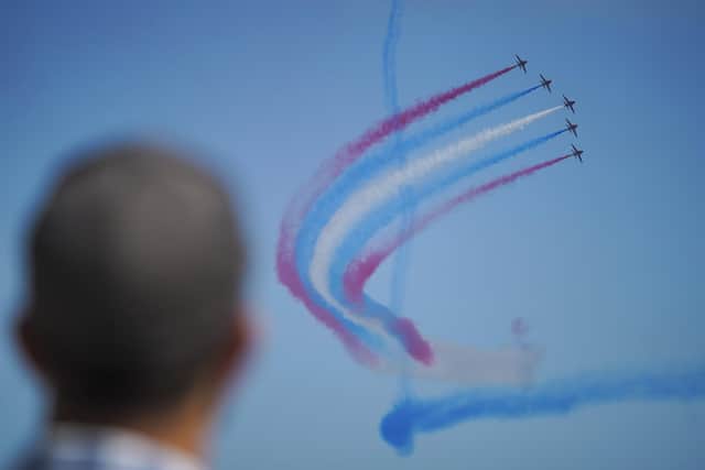FALMOUTH, ENGLAND - JUNE 24: A member of the public watches the Red Arrows fly over Gyllyngvase Beach during Armed Forces Day on June 24, 2023 in Falmouth, England. Events are being held across the United Kingdom to celebrate Armed Forces Day, highlighting the work that the UK Armed Forces do in keeping the people of the United Kingdom safe.  In Falmouth, the host location of this yearâ€™s National Event, members of the Armed Forces took part in a tri-service parade which is set to feature more than 1,000 military personnel, veterans and cadets. (Photo by Hugh Hastings/Getty Images)