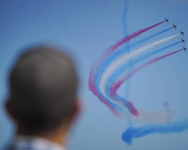 FALMOUTH, ENGLAND - JUNE 24: A member of the public watches the Red Arrows fly over Gyllyngvase Beach during Armed Forces Day on June 24, 2023 in Falmouth, England. Events are being held across the United Kingdom to celebrate Armed Forces Day, highlighting the work that the UK Armed Forces do in keeping the people of the United Kingdom safe.  In Falmouth, the host location of this yearâ€™s National Event, members of the Armed Forces took part in a tri-service parade which is set to feature more than 1,000 military personnel, veterans and cadets. (Photo by Hugh Hastings/Getty Images)