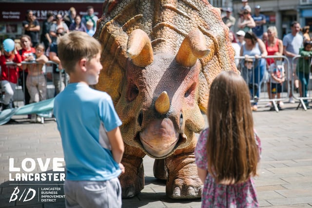 One of the dinosaurs at Dino Fest in front of two children who want to meet it. Picture by Ginny Koppenhol.