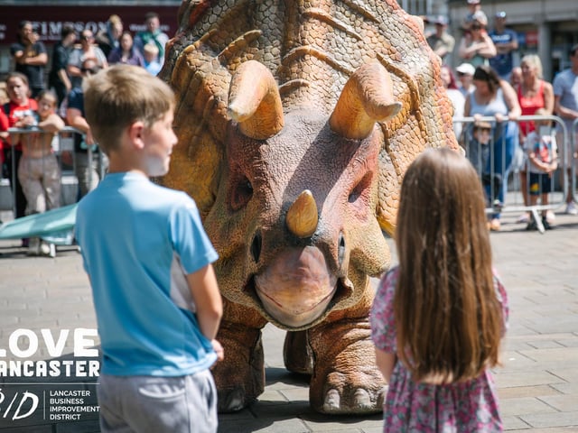 One of the dinosaurs at Dino Fest in front of two children who want to meet it. Picture by Ginny Koppenhol.
