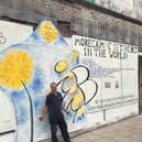 Nick Smith with the bee mural on the front of the Queen's Market in Victoria Street.