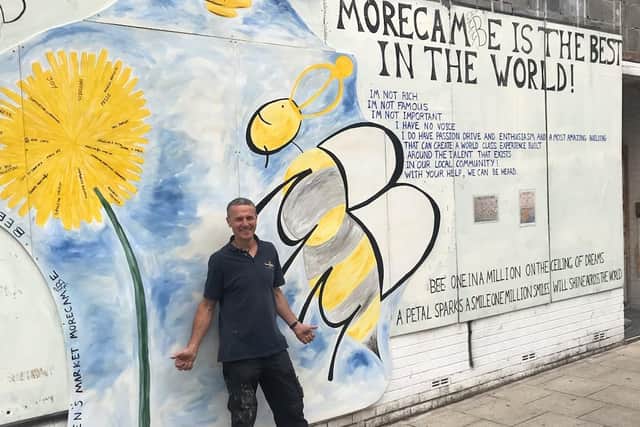 Nick Smith with the bee mural on the front of the Queen's Market in Victoria Street.