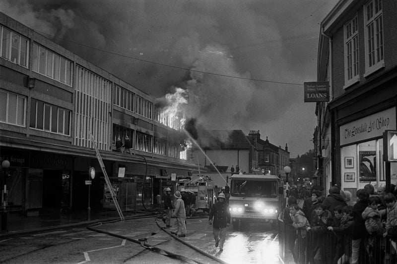 Flames leap from the market windows as the fire rages and crowds gather.