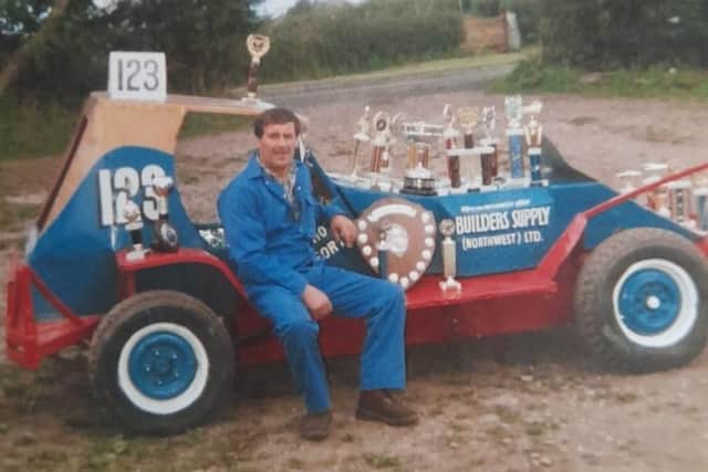 Gerald Hoggarth sitting on his stock car with all his trophies.