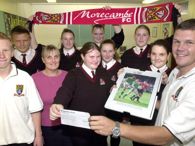 Morecambe FC player Michael Knowles receives a cheque from pupils of Morecambe High School who staged a special fundraising football-themed evening for the injured Shrimps' star. The evening was organised by teacher Linda Hartley. Michael presented the children with a signed picture of himself in action and some tickets for the weekend's game against Dover as a thank you. Also on the picture is defender David Perkins, a former Morecambe High School pupil.