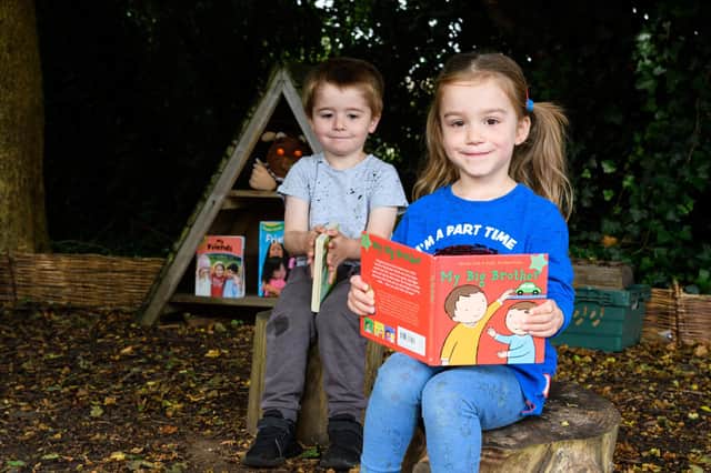 Pupils at Mossgate Day Nursery read a book in their new outdoor space. Photo: Kelvin Stuttard