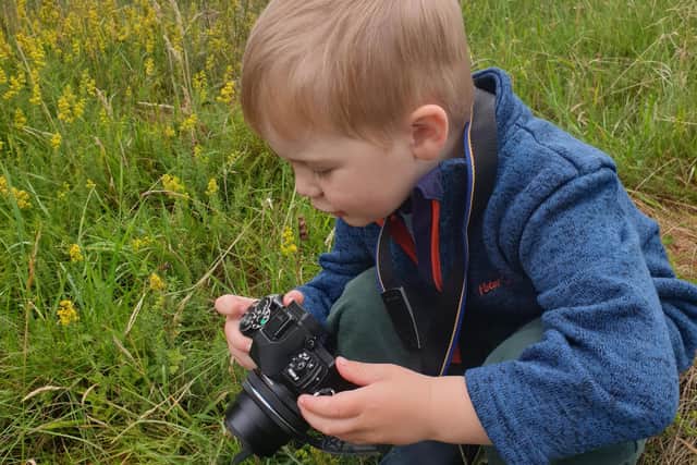 A boy uses his camera in the outdoors.