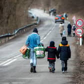 A woman with two children and carrying bags walk on a street to leave Ukraine after crossing the Slovak-Ukrainian border in Ubla, eastern Slovakia, close to the Ukrainian city of Welykyj Beresnyj, following Russia's invasion of the Ukraine. Photo by PETER LAZAR/AFP via Getty Images