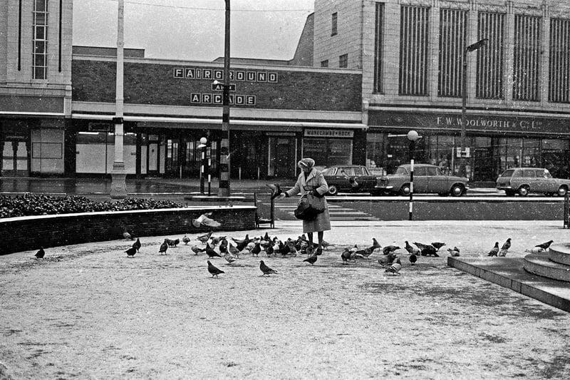 Feeding the birds in front of the former Woolworth store, and fairground and arcade entrance.
