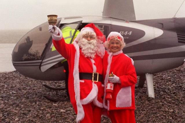 Father Christmas and Mrs Christmas arrive by helicopter on Morecambe beach during heavy rainfall in 1999