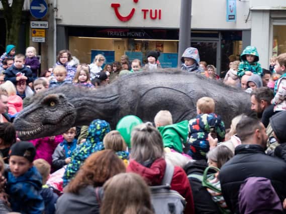 Rex the T-Rex rages through Lancaster city centre as the crowds watch on.