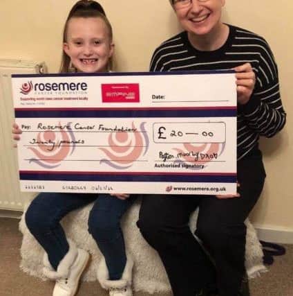 A gappy grin from Payton as she presents Rosemere Cancer Foundations Julie Hesmondhalgh with her tooth fairy money donation.
