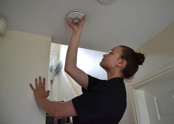 Merseyside Fire and Rescue Service apprentice Jessica Lewis fitting a smoke alarm.