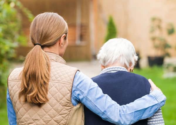 STOCK PHOTO: A young carer walking with an elderly woman.