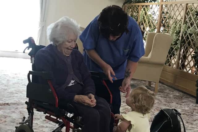 A resident of Hillcroft nursing home meets one of the babies that visited.