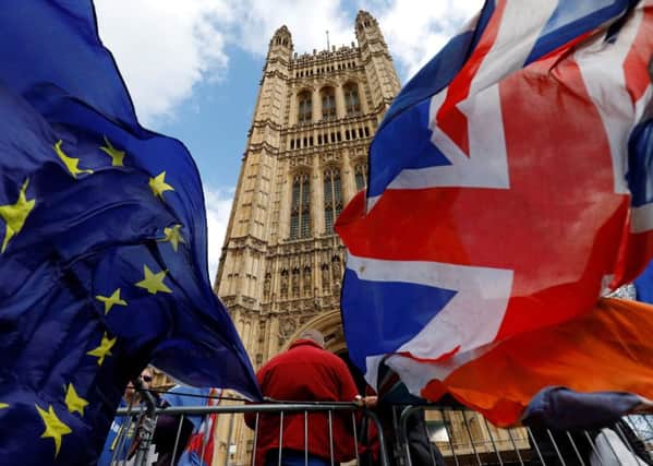 Pro-Brexit and anti-Brexit protesters hold flags as they demonstrate outside the Houses of Parliament in London on March 14, 2019 as members debate a motion on whether to seek a delay to Britain's exit from the EU. - MPs vote on March 14 on whether to seek a Brexit delay, as the chaotic process to end Britain's 46-year membership of the EU plunges the country into deep political crisis. (Photo by Tolga AKMEN / AFP)        (Photo credit should read TOLGA AKMEN/AFP/Getty Images)
