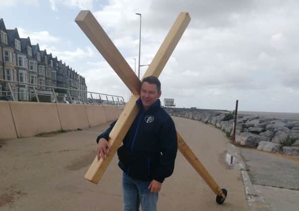 Paul Mclachlan carrying a cross on Morecambe seafront.