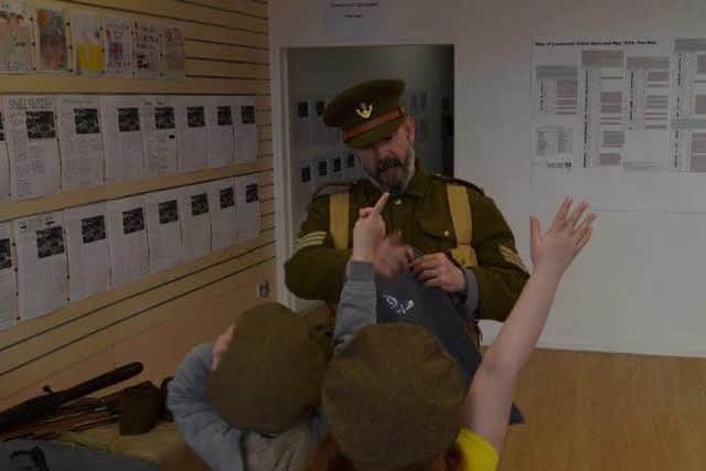 Two young visitors learn more about life in the trenches with World War I soldier (Dave Casserly, Lancashire County Council Heritage Learning Team).