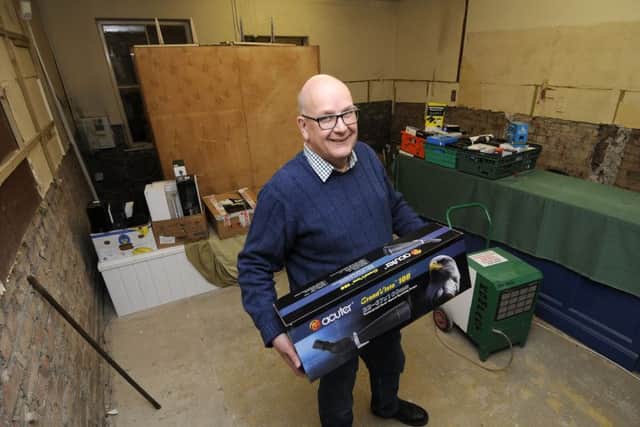 Andrew Ireland keeps smiling as his shop undergoes major repairs following the flooding.