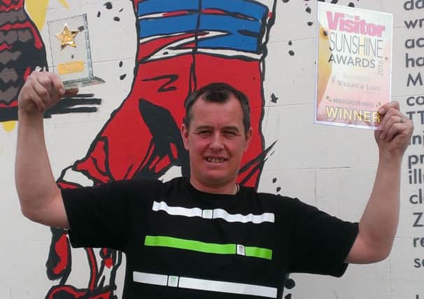 John McGuinness with The Visitor Sunshine Ambassador Award and the new mural in Morecambe paying tribute to his motorcycling achievements.