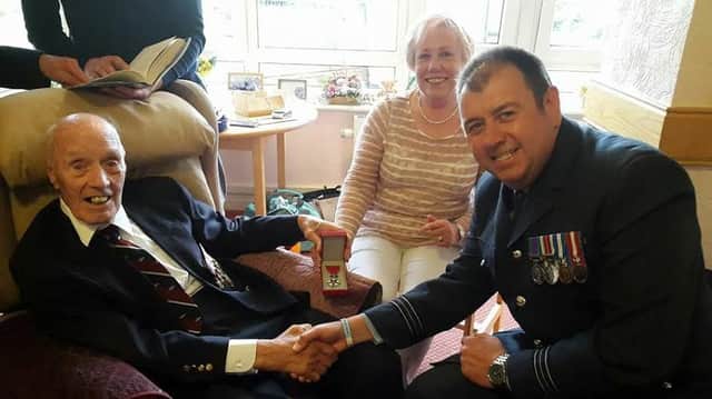 Ronald Meadows pictured shaking hands with squadron leader John Barlow. Ron's daughter, Barbara Williams, is holding the medal.