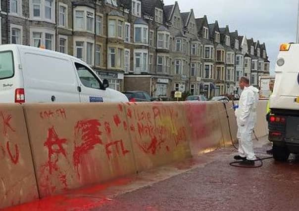 Graffiti is removed from the newly rebuilt Wave Reflection Wall on Marine Road East on Friday morning. Photo by Linda Walker.