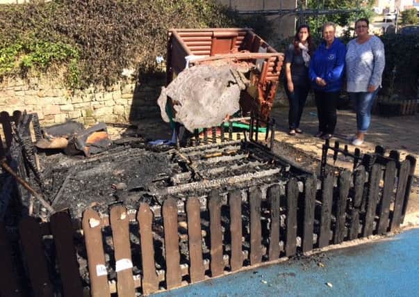 Owners of Time 4 Nursery Laura Morgans (left) and Sarah Rodriguez (right) with nursery manager Doreen Johnson, survey the charred remains of a wooden playhouse.