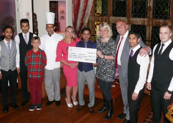 Julie and Andrew Seaton hand over a cheque for the money they raised at the Babar Elephant restaurant in Lancaster.