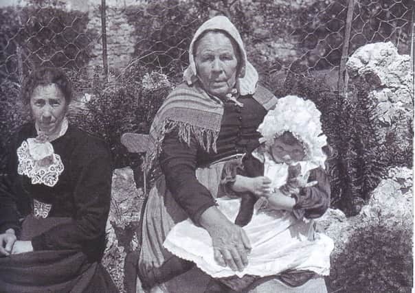 Anne Holmes, right (80-years-old), her daughter Elizabeth Moss (35-years-old) and granddaughter Mary A. Moss (seven-years-old) at Walnut Cottage, no.51 The Row, Silverdale in 1907. Ann was a widow but made a living as a laundress with her daughter. Ann is wearing clothes typical of the older working women of the time. Caps, shawls and wraparound pinafores were the order of the day