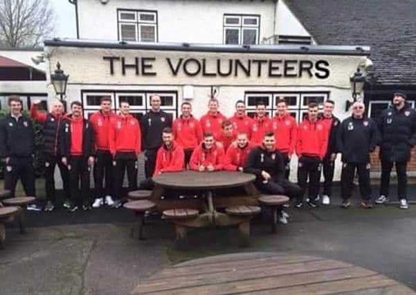 The Morecambe football team showing humour outside an appropriately-named pub in the London area before their League Two match with Leyton Orient on Tuesday. This photo was taken before it was confirmed that the team and other staff had been paid their wages.