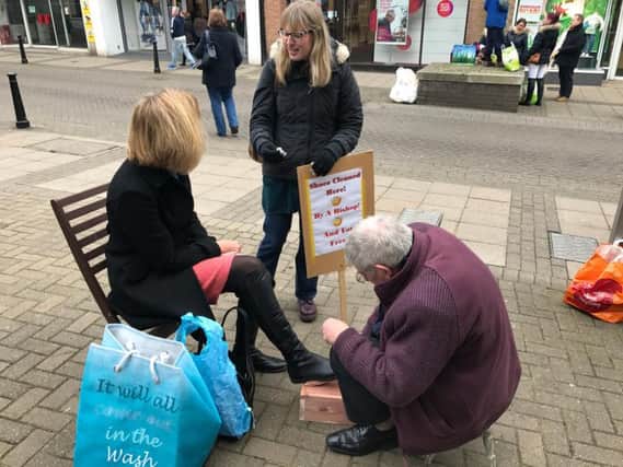 Bishop of Lancaster, Rt Rev. Geoff Pearson, gets down to work shoe shining in Bishop Auckland while Hannah Boyd, Curate at Layton St Mark's, Blackpool, chats to his client