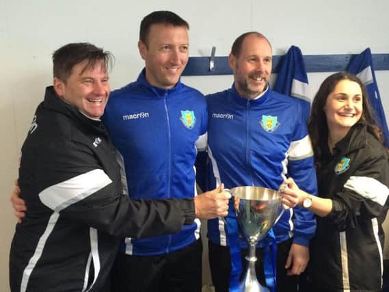 Phil Brown, second from right, and his coaching staff with the trophy.
