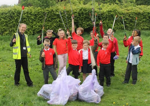 Lauren Gora, Lancaster City Council Waste and Recycling Officer, helps pupils clear rubbish from  school land.