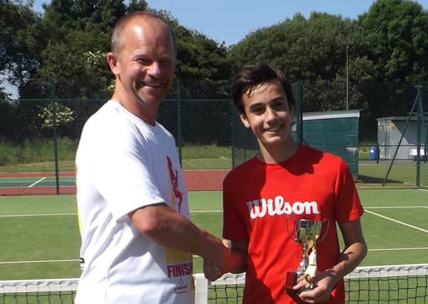 Tournament referee and tennis coach Eden Parkinson presenting the trophy to U16 champion Javier Guillen.