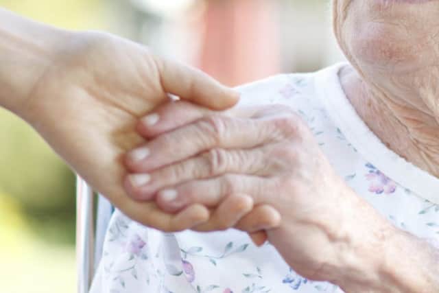 A woman holding hands with a carer.