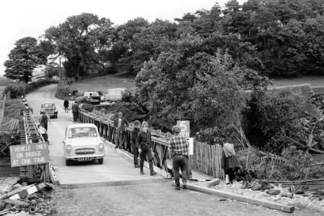 Bailey Bridge over the River Hindburn, Wray to Wennington road, August 1967.
Lancashire County Council erected this bridge five days after the flood destroyed Mealbank Bridge, the remains of which can be seen to the right of the photograph.
The firm of Thomas Fletcher and Company later built a new bridge of steel and concrete.
The last bridge to be destroyed by the flood was the disused railway bridge over the River Wenning. This bridge carried the railway line from Wennington to Lancaster.