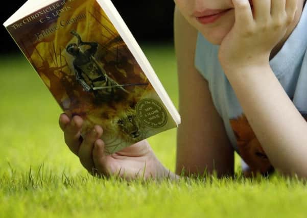 A  child reading a book. Schoolchildren are being urged to write their own Christmas story to win prizes for their school.