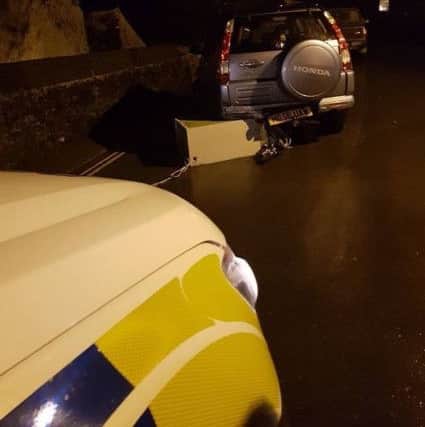 The ATM wedged under a parked car. Thanks to Thomas Beresford and Sarah Louise Ellwood for the photos.