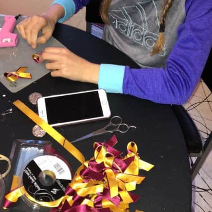 Georgia Thornton making the ribbons she has been selling for charity.
